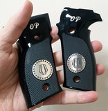  black textured pistol grip with a silver circular emblem and 'OP' lettering, held in a person's hand against a plain light background.