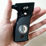 A black textured pistol grip with a silver circular emblem and 'OP' lettering, held in a person's hand against a plain light background.