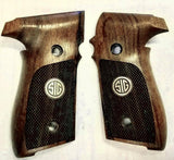 A pair of wooden pistol grips with dark textured panels and a silver-toned circular 'SIG' logo, displayed on a light background.