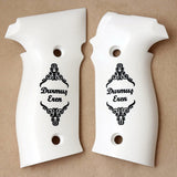 A pair of white pistol grip covers with black ornate scrollwork and the text 'Durmuc Eren' printed on each, displayed on a tan background.