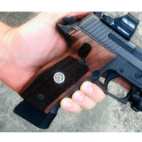 Sig Sauer P228 custom grips made from walnut wood with silver logo inlay, showcasing detailed craftsmanship and natural wood grain.