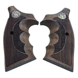 A pair of dark brown wooden pistol grips with textured checkering, a central recessed grip panel, and a silver circular metal emblem near the top, shown on a plain white background.