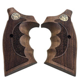 A pair of dark brown wooden pistol grips with textured checkering, featuring a gold-toned circular emblem near the top and a central recessed grip panel, shown on a plain white background.